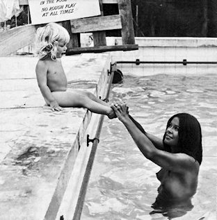 Woman in pool holding toddler's feet